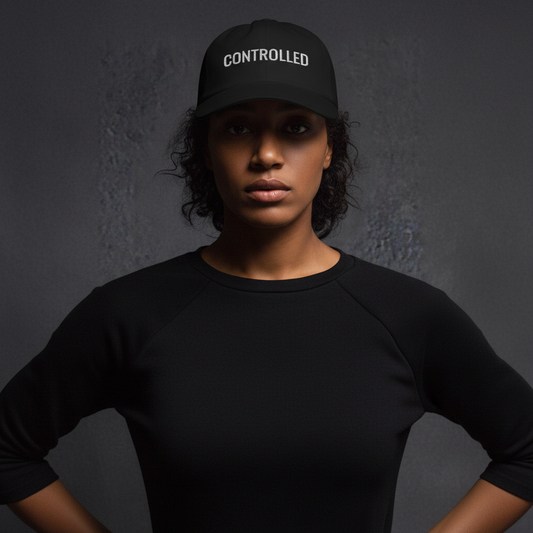 Black cap with CONTROLLED text worn by model, minimal streetwear style, calm and focused expression